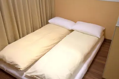 a bed with two pillows on top of it at \u4e0a\u91ce\u4e4b\u5bb6Vip\u5bb6\u5ead\u623f in Tokyo
