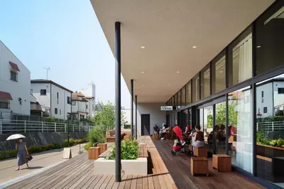 a building with people sitting on a wooden deck at MUSTARD HOTEL SHIMOKITAZAWA in Tokyo