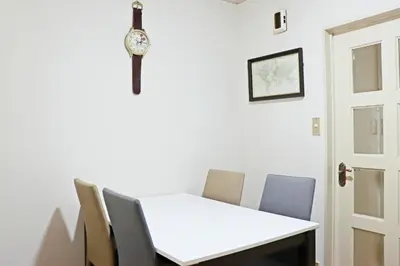 a white table with chairs and a clock on the wall at NAVI Azabujuban in Tokyo
