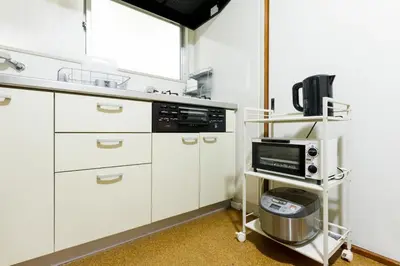 a kitchen with white cabinets and a microwave at NAVI Azabujuban in Tokyo