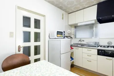 a kitchen with white cabinets and a table and a microwave at NAVI Azabujuban in Tokyo