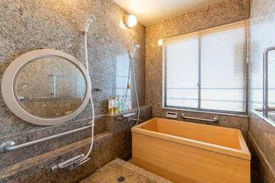 a bathroom with a large mirror and a tub at Futaba Hotel in Tokyo