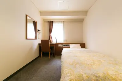 a bedroom with a bed and a desk and a window at Hotel Ohedo in Tokyo