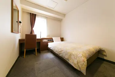 a bedroom with a bed and a desk and a window at Hotel Ohedo in Tokyo