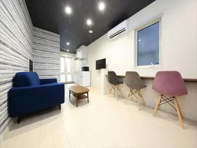 a living room with a blue couch and two chairs at COTO Tokyo Koenji in Tokyo