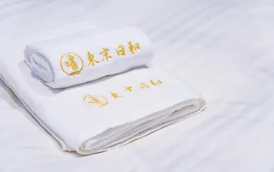 a white towel with gold writing on it on a bed at \u6771\u4eac\u65e5\u548c in Tokyo