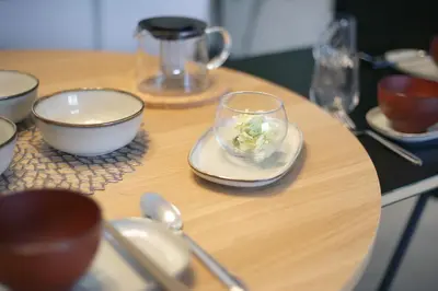 a wooden table topped with bowls and a bowl of greens at Green Sea Oshiage in Tokyo