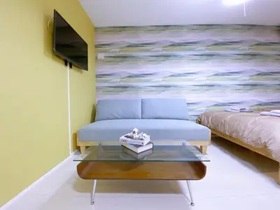 a living room with a couch and a painting at nestay apartment tokyo ginza in Tokyo