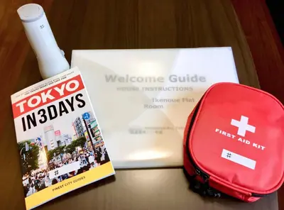 a book and a red suitcase next to a welcome guide at Shibuya \u6e0b\u8c37 \u4e0b\u5317\u6ca2\u30a8\u30ea\u30a2 \u96fb\u52d5\u30ad\u30c3\u30af\u30dc\u30fc\u30c9LUUP\u6577\u5730\u5185 \u99c5\u5f92\u6b693\u5206 in Tokyo