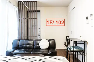 a living room with a black leather couch and a table at Shibuya \u6e0b\u8c37 \u4e0b\u5317\u6ca2\u30a8\u30ea\u30a2 \u96fb\u52d5\u30ad\u30c3\u30af\u30dc\u30fc\u30c9LUUP\u6577\u5730\u5185 \u99c5\u5f92\u6b693\u5206 in Tokyo