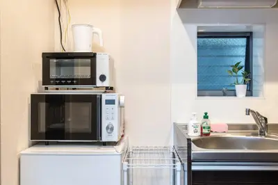 a kitchen with a microwave and a sink at Shibuya \u6e0b\u8c37 \u4e0b\u5317\u6ca2\u30a8\u30ea\u30a2 \u96fb\u52d5\u30ad\u30c3\u30af\u30dc\u30fc\u30c9LUUP\u6577\u5730\u5185 \u99c5\u5f92\u6b693\u5206 in Tokyo