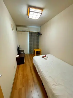 a bedroom with a bed and a desk and a window at Uhome Kamiitabashi Apartment in Tokyo