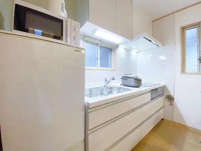 a white kitchen with a sink and a microwave at nestay villa tokyo takanawa in Tokyo