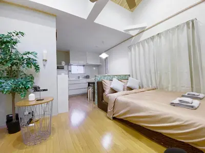 a bedroom with a large bed and a kitchen at nestay villa tokyo takanawa in Tokyo