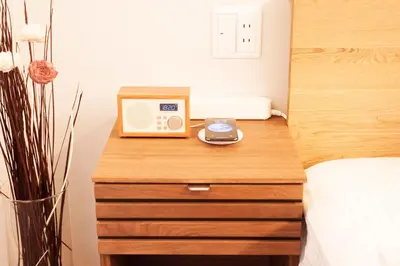 a wooden table with a clock on top of a bed at Monoka Hotel Ginza in Tokyo