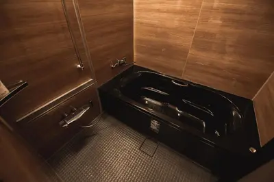 a bathroom with a black sink and wooden walls at Monoka Hotel Ginza in Tokyo