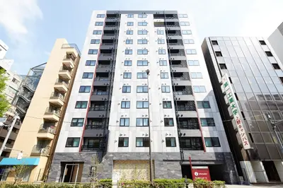 a tall white building with windows at MONday Apart Premium UENO in Tokyo