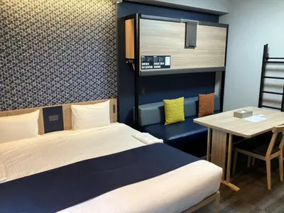 a room with two beds and a table and a table and a bed at MONday Apart Premium Ginza Shintomicho in Tokyo
