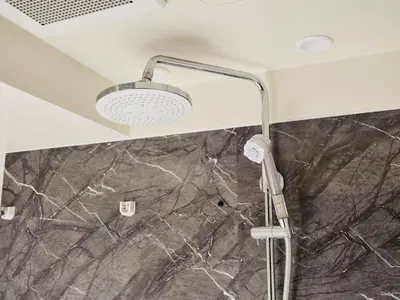 a shower head in a bathroom with a marble wall at MONday Apart Premium Ginza Shintomicho in Tokyo
