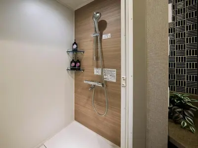 a shower in a bathroom with a wooden wall at Minn Kasai in Tokyo