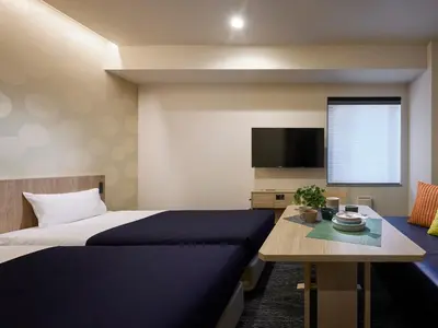 a bedroom with a bed and a table and a tv at Minn Kasai in Tokyo