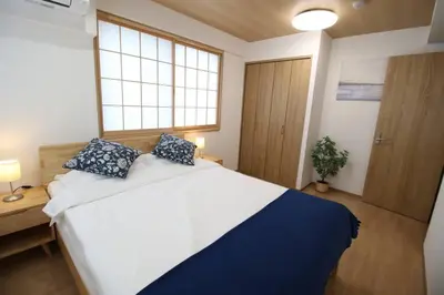 a bedroom with a large white bed with blue pillows at Uhome Suido Apartment SD in Tokyo