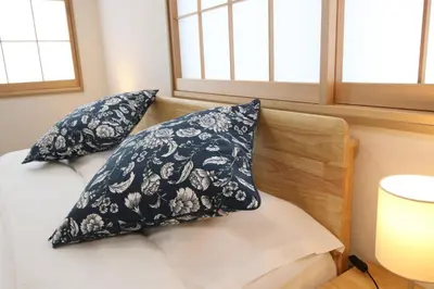 two pillows on a bed in a room with windows at Uhome Suido Apartment SD in Tokyo