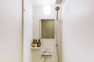 a bathroom with a shower with a mirror and a sink at &AND HOSTEL ASAKUSA KAPPABASHI in Tokyo