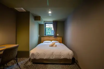 a bedroom with a bed and a desk and a window at Wise Owl Hostels River Tokyo in Tokyo
