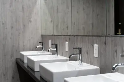 a row of sinks in a public bathroom at Wise Owl Hostels River Tokyo in Tokyo