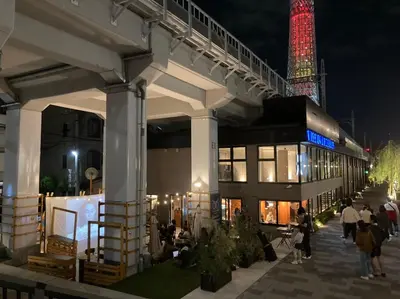 a group of people standing outside of a building at night at Wise Owl Hostels River Tokyo in Tokyo