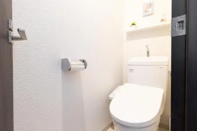 a white toilet in a bathroom with a toilet paper dispenser at Peace Inn Skytree Tokyo in Tokyo