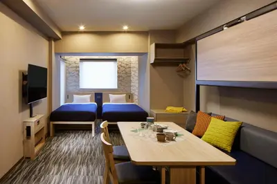 a room with two beds and a table and a couch at Minn Akihabara in Tokyo