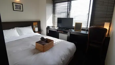 a bedroom with a bed and a desk with a television at Sutton Place Hotel Ueno in Tokyo