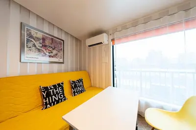 a room with a yellow couch and a table and a window at La Krasse Skytree in Tokyo