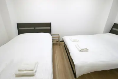 two beds in a room with white sheets and wooden floors at Uhome\u5343\u99c4\u6728\u9759\u96c5\u6c11\u5bbf\u65c5\u9986 in Tokyo