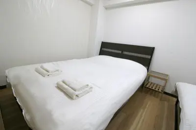 a bedroom with a bed with white sheets and towels at Uhome\u5343\u99c4\u6728\u9759\u96c5\u6c11\u5bbf\u65c5\u9986 in Tokyo