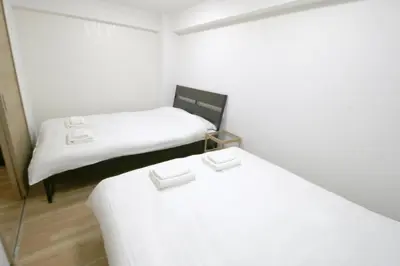 two beds in a small room with white sheets at Uhome\u5343\u99c4\u6728\u9759\u96c5\u6c11\u5bbf\u65c5\u9986 in Tokyo