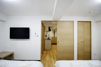 a bedroom with two beds and a television on a wall at Uhome\u5343\u99c4\u6728\u9759\u96c5\u6c11\u5bbf\u65c5\u9986 in Tokyo
