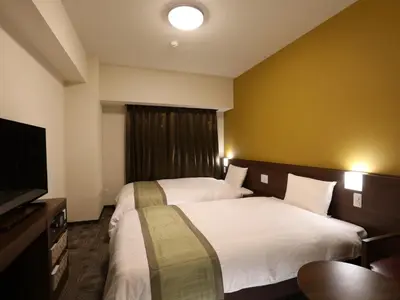 a hotel room with two beds and a flat screen tv at Dormy Inn Ikebukuro - Natural Hot Spring in Tokyo