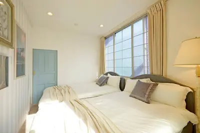 a bedroom with a bed with white sheets and a window at Meee Shinjuku in Tokyo
