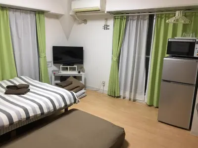 a room with two beds and a television and green curtains at Isshuku Ryokan Asakusabashi - Vacation STAY 17365v in Tokyo