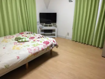a bedroom with a bed and a tv and green curtains at Isshuku Ryokan Asakusabashi - Vacation STAY 17365v in Tokyo