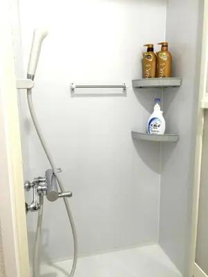 a shower in a bathroom with shelves on the wall at Isshuku Ryokan Asakusabashi - Vacation STAY 17353v in Tokyo