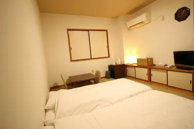 a bedroom with a bed and a desk with a television at Okubo Hotel Hawaii in Tokyo