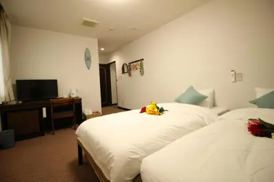 a hotel room with two beds and a television at Okubo Hotel Hawaii in Tokyo