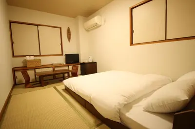 a hotel room with two beds and a desk at Okubo Hotel Hawaii in Tokyo