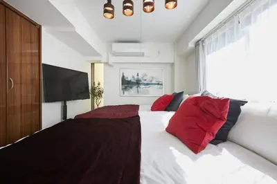 a bedroom with a large bed with red pillows at HOTEL AIS HATAGAYA in Tokyo