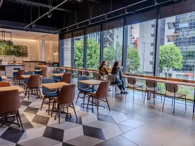 two women sitting at tables in a restaurant with large windows at Tokyu Stay Shinjuku Eastside in Tokyo