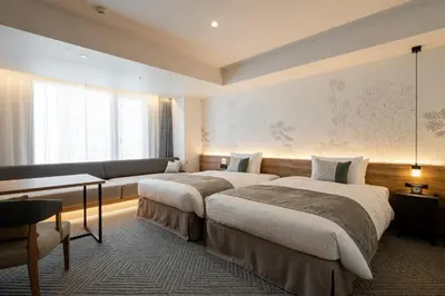 a hotel room with two beds and a couch at Tokyu Stay Shinjuku Eastside in Tokyo